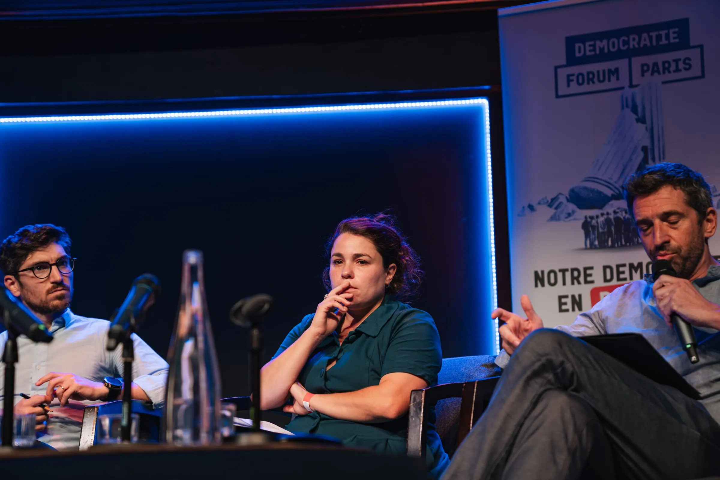 Trois intervenant·es en table ronde, l'un d'eux au micro.