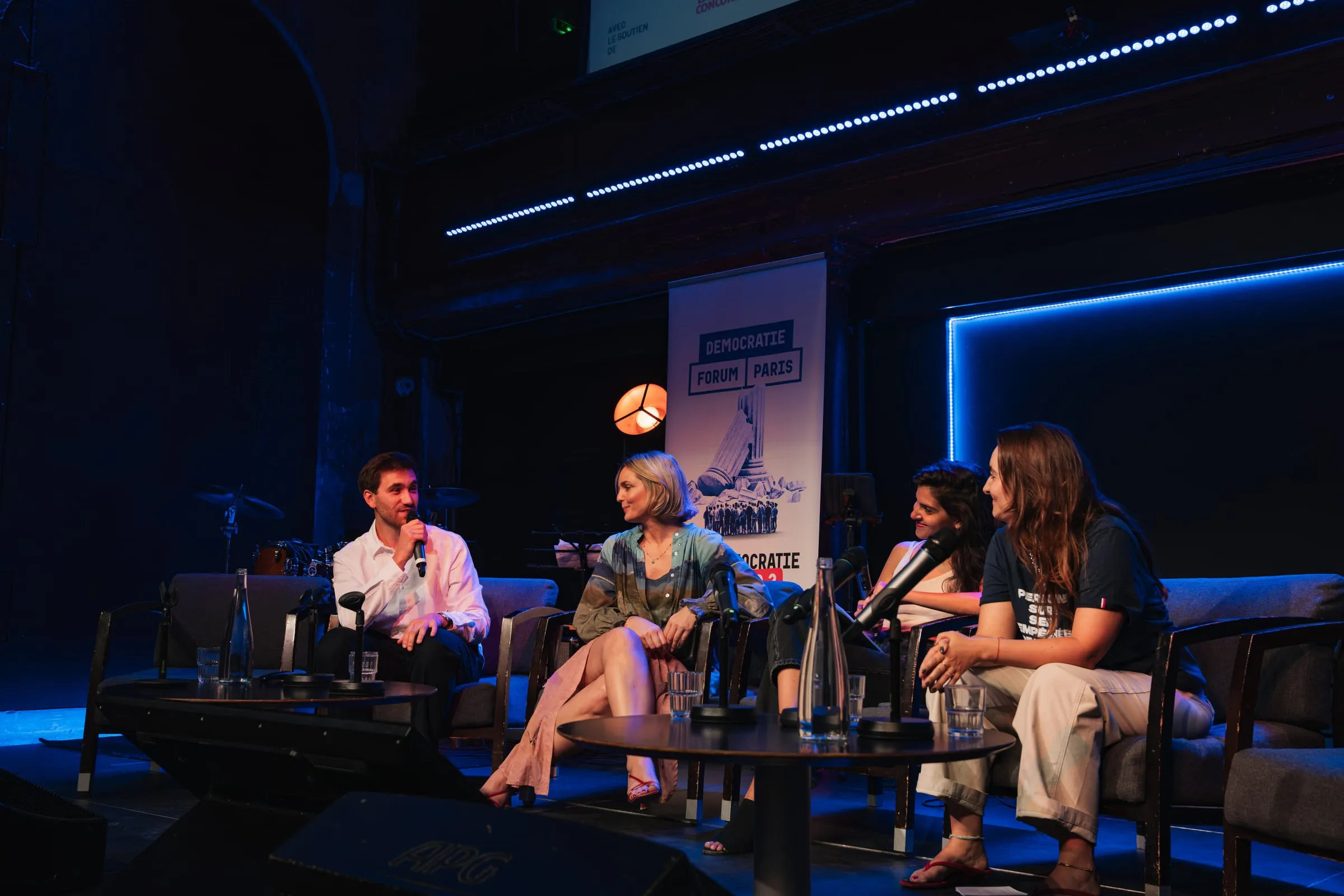 Quatre intervenant·es en table ronde sur la scène du forum, micro à la main.