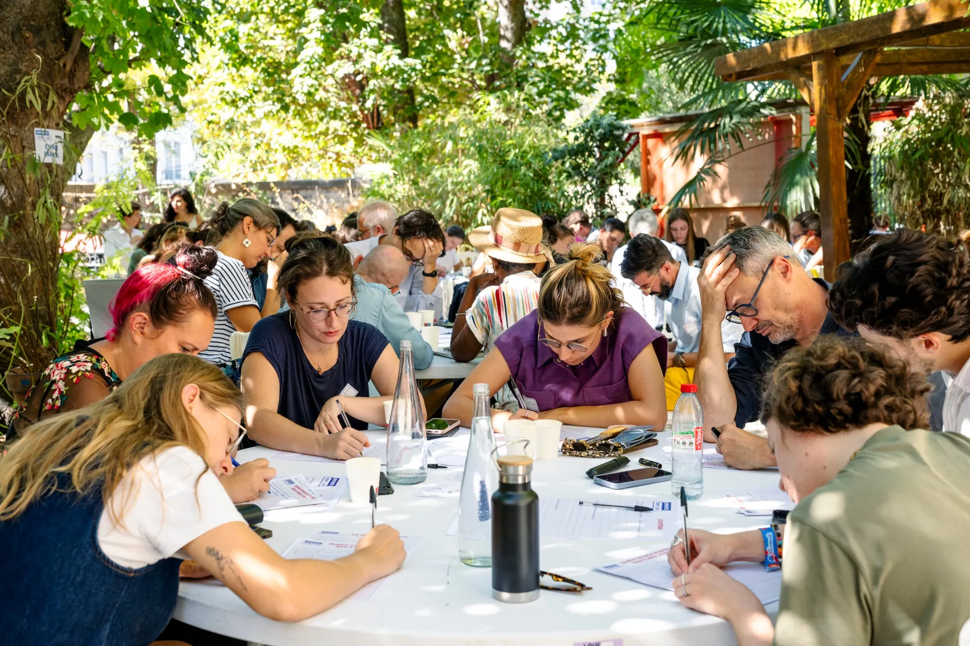 Participants attablés en plein air, en train d'écrire pendant le workshop.